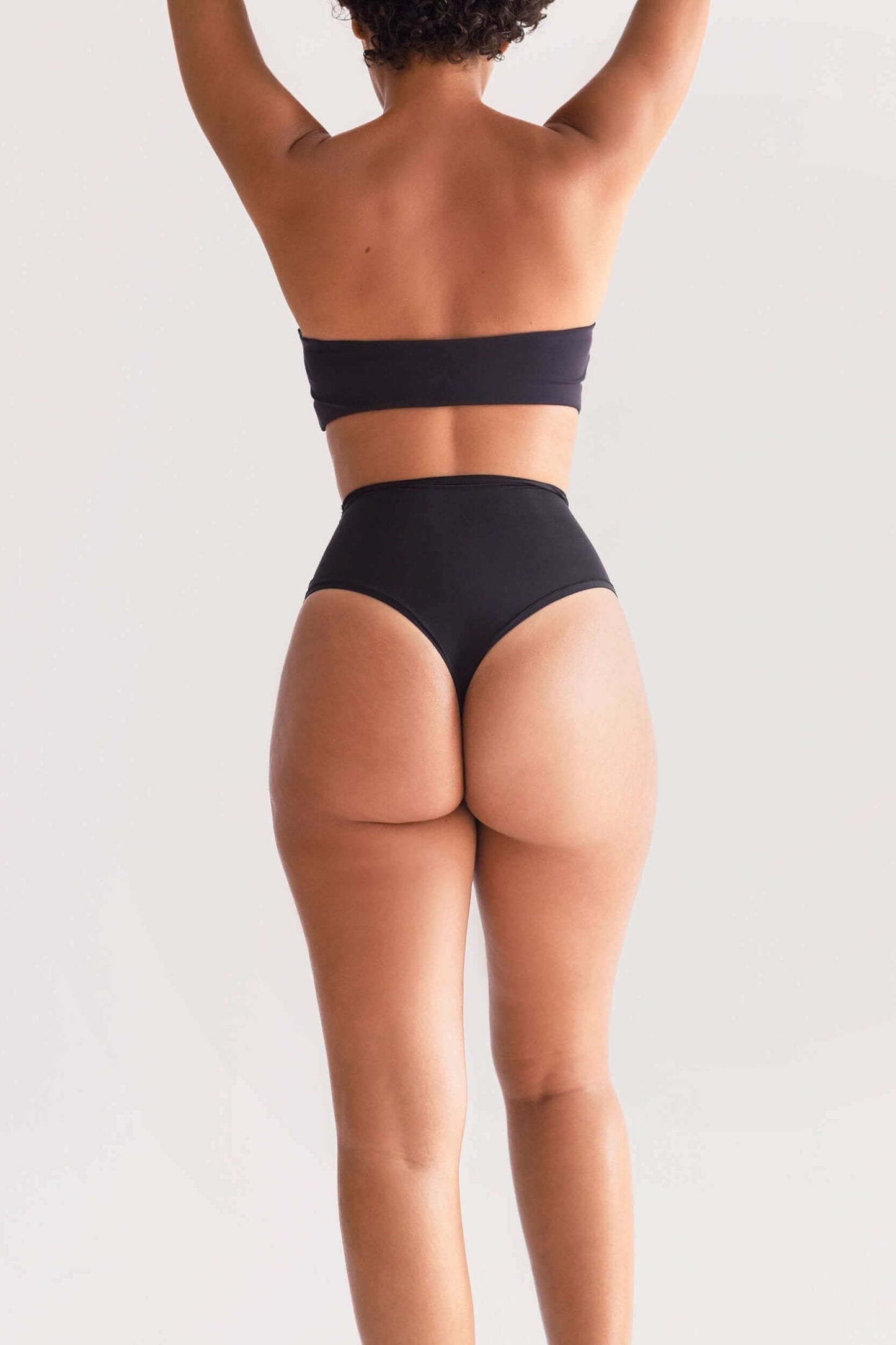 Model wearing UNDRESSE High-Waist Thong in Black Back Side
